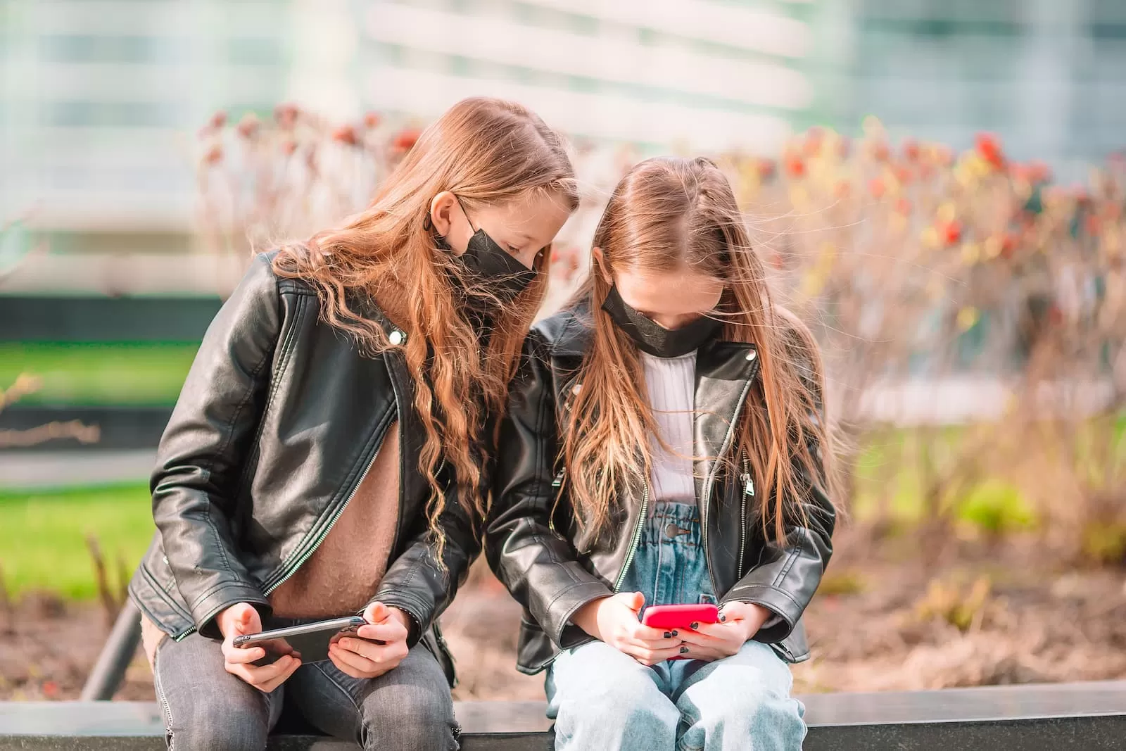 dos chicas sentadas en un banco con movil la nueva normalidad