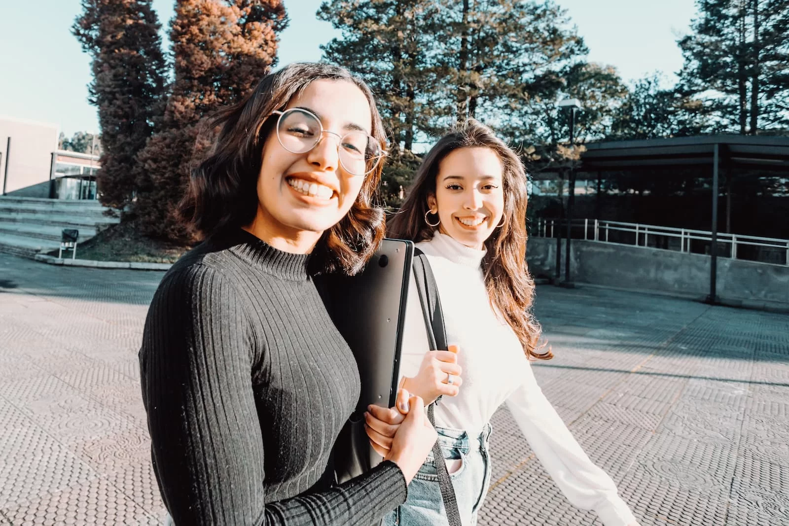 dos chicas universitarias alegres sonrien a camara mientras van a clase