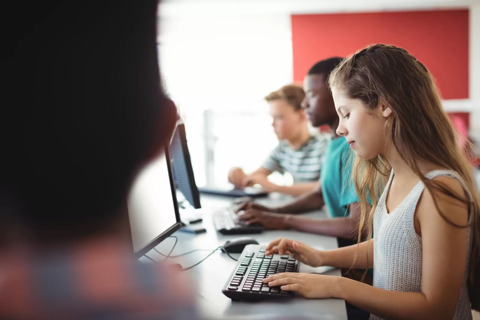 estudiante pequeña rubia utiliza ordenador en clase